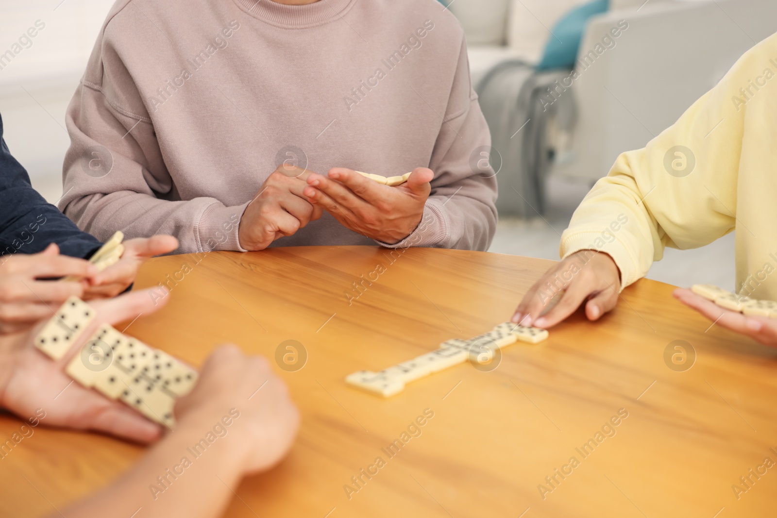 Friends playing dominoes at wooden table indoors, closeup Photo of Friends playing dominoes at wooden table indoors, closeup