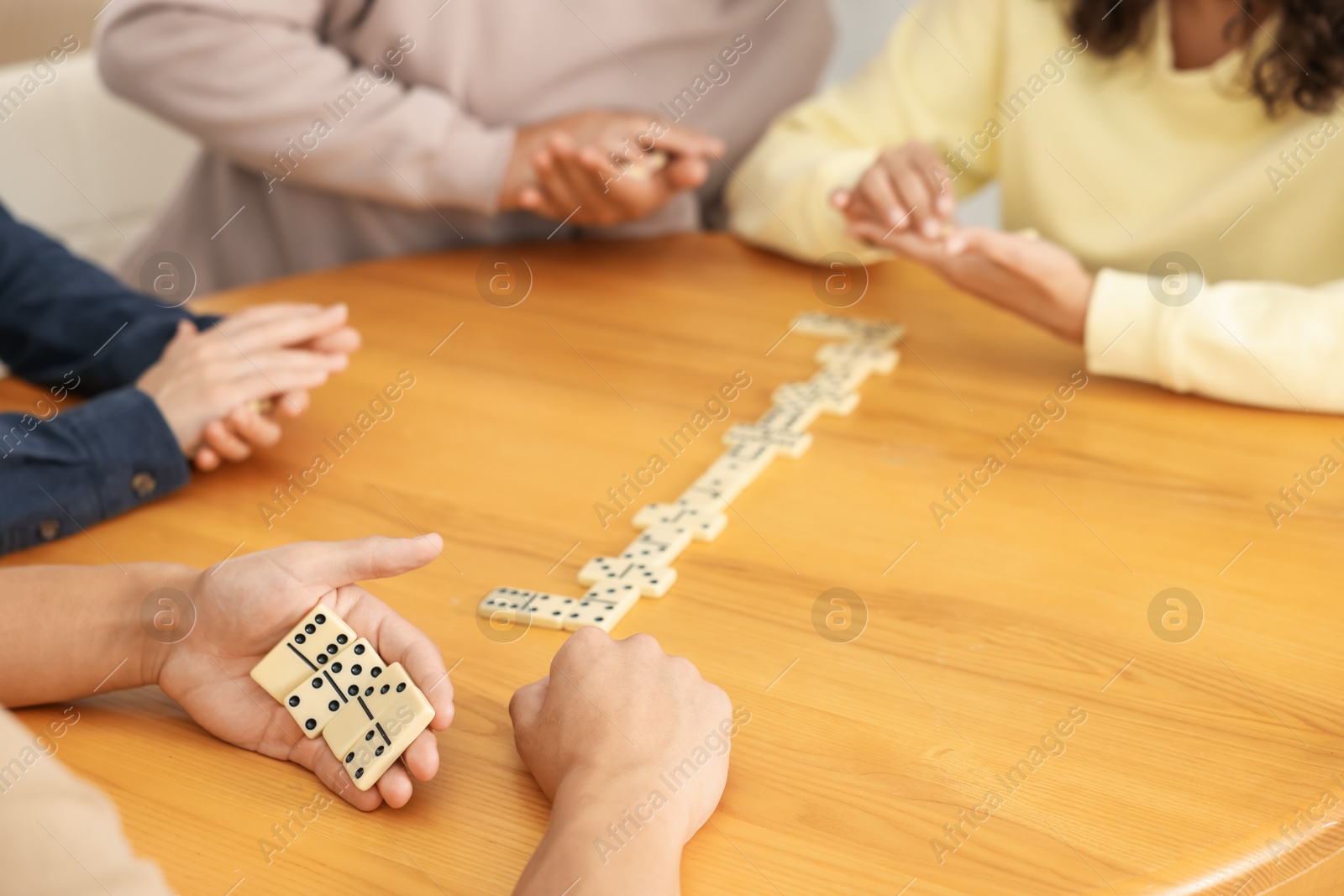 Friends playing dominoes at wooden table, closeup Photo of Friends playing dominoes at wooden table, closeup