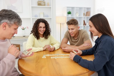 Photo of Friends playing dominoes at wooden table indoors