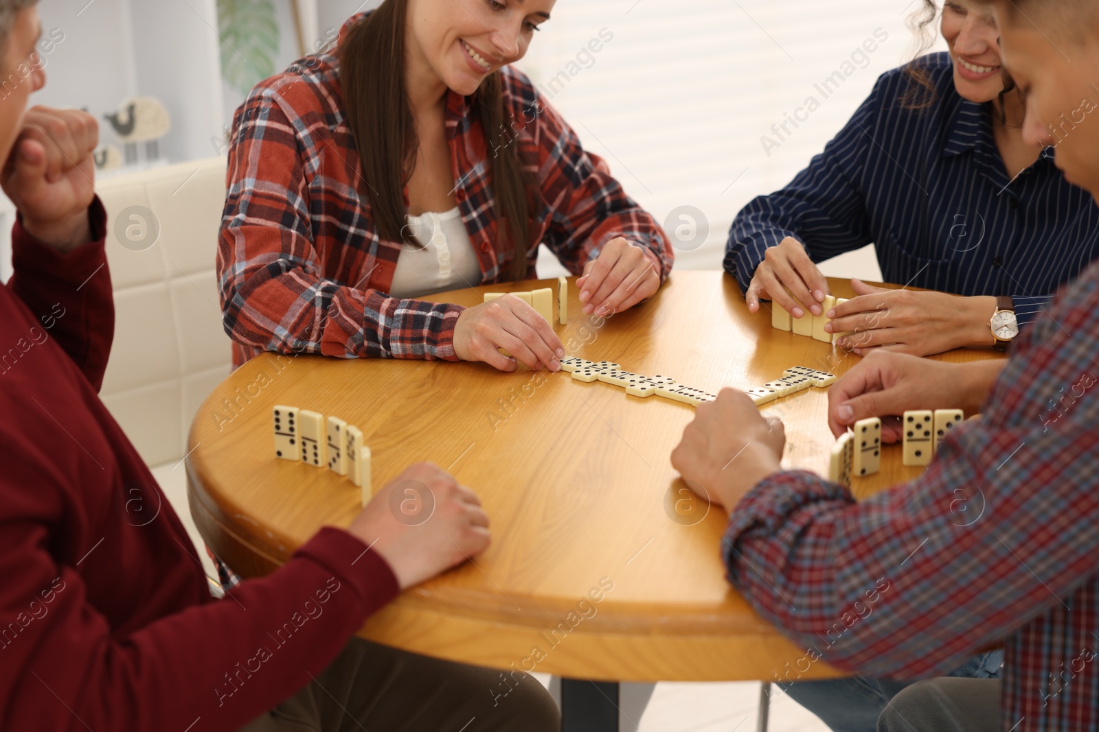 Friends playing dominoes at wooden table indoors, closeup Photo of Friends playing dominoes at wooden table indoors, closeup