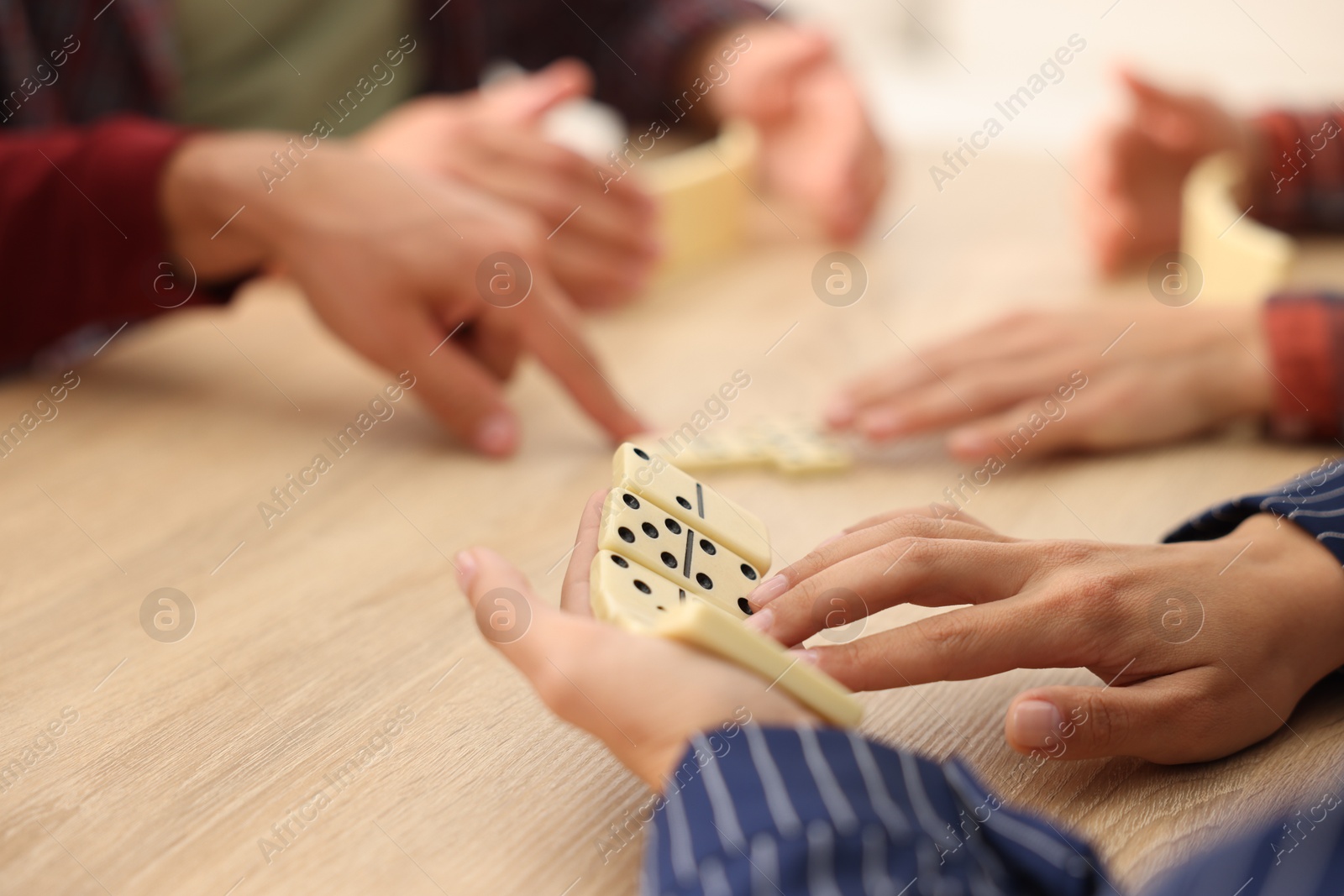 Friends playing dominoes at light wooden table, closeup Photo of Friends playing dominoes at light wooden table, closeup