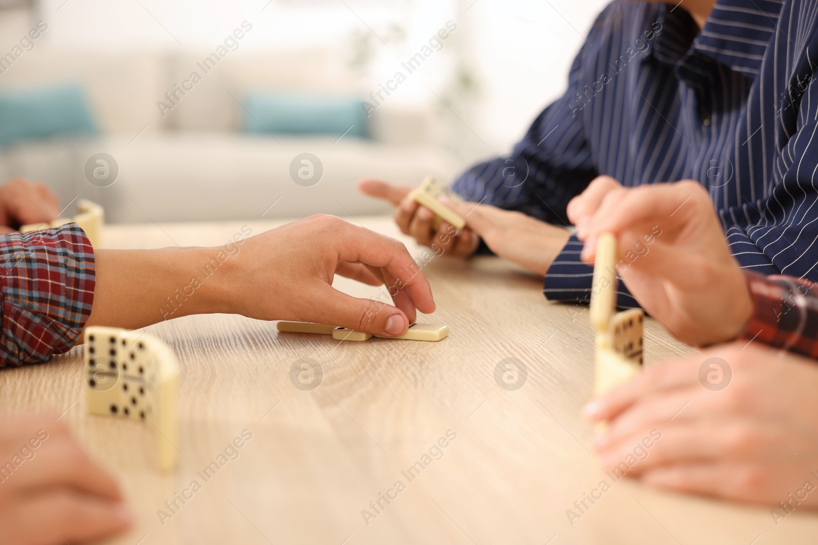 Friends playing dominoes at light wooden table indoors, closeup Photo of Friends playing dominoes at light wooden table indoors, closeup