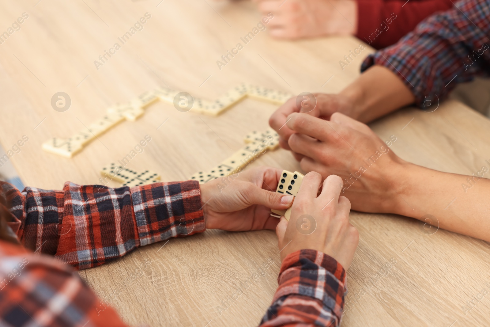 Friends playing dominoes at light wooden table, closeup Photo of Friends playing dominoes at light wooden table, closeup