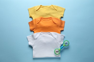 Photo of Baby clothes and accessory on light blue background, flat lay
