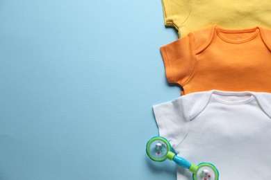 Photo of Baby clothes and accessory on light blue background, flat lay. Space for text