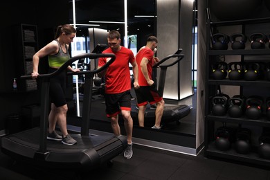 Photo of Young woman exercising on treadmill with professional personal trainer in gym