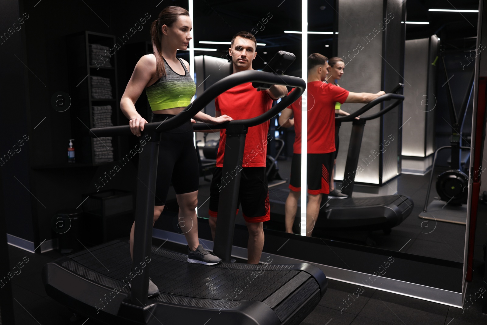 Young woman exercising on treadmill with professional personal trainer in gym Photo of Young woman exercising on treadmill with professional personal trainer in gym