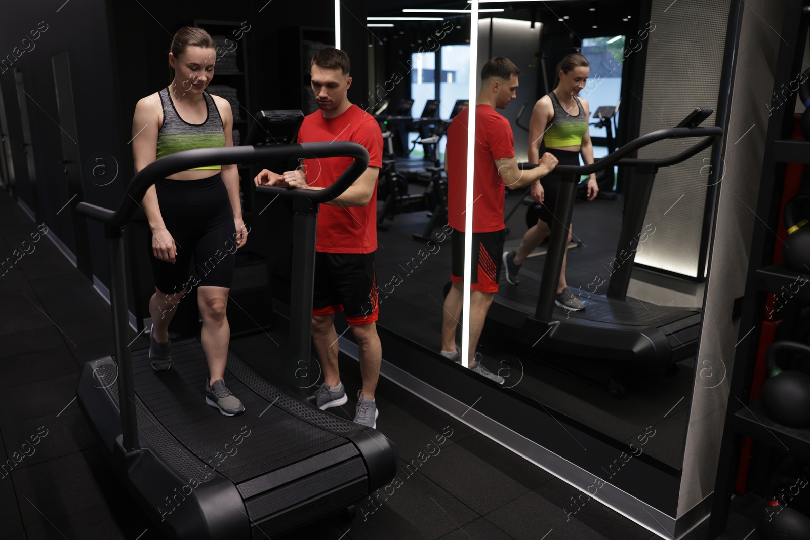 Young woman exercising on treadmill with professional personal trainer in gym Photo of Young woman exercising on treadmill with professional personal trainer in gym