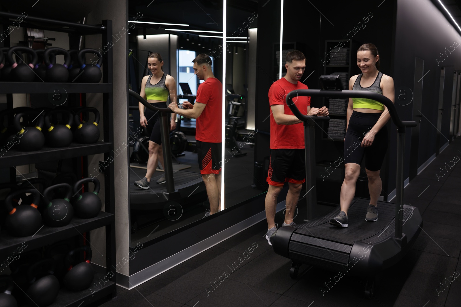 Young woman exercising on treadmill with professional personal trainer in gym Photo of Young woman exercising on treadmill with professional personal trainer in gym