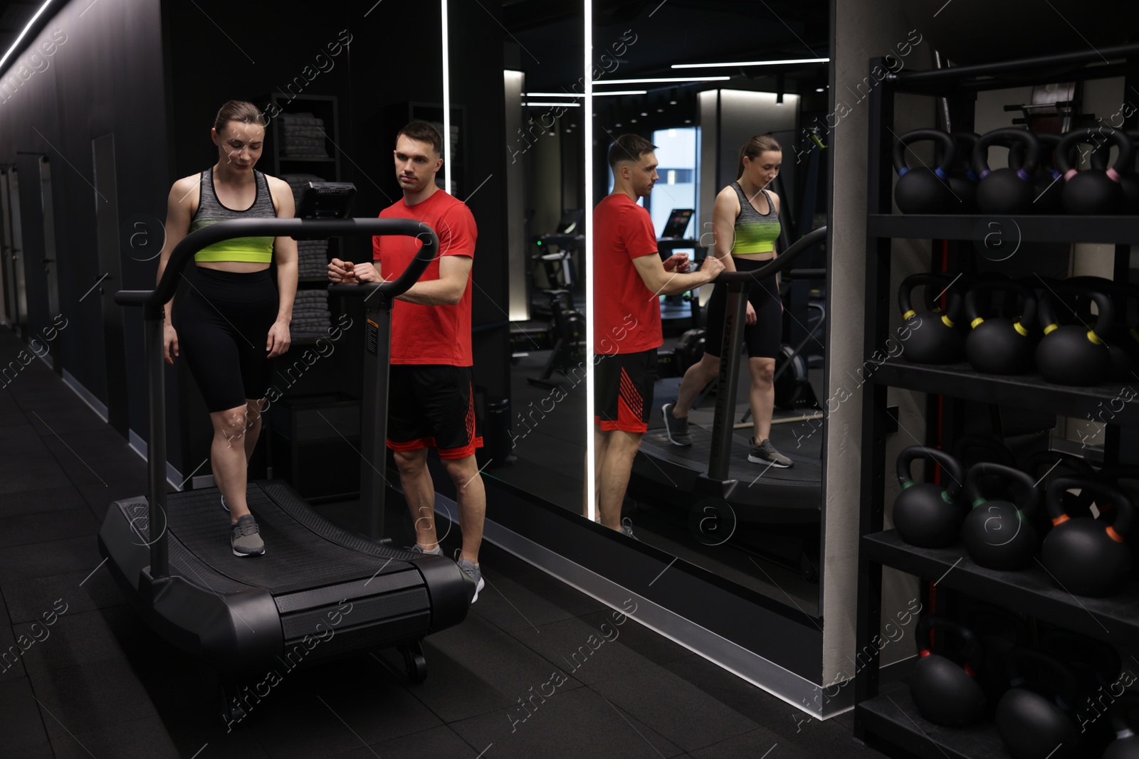 Young woman exercising on treadmill with professional personal trainer in gym Photo of Young woman exercising on treadmill with professional personal trainer in gym