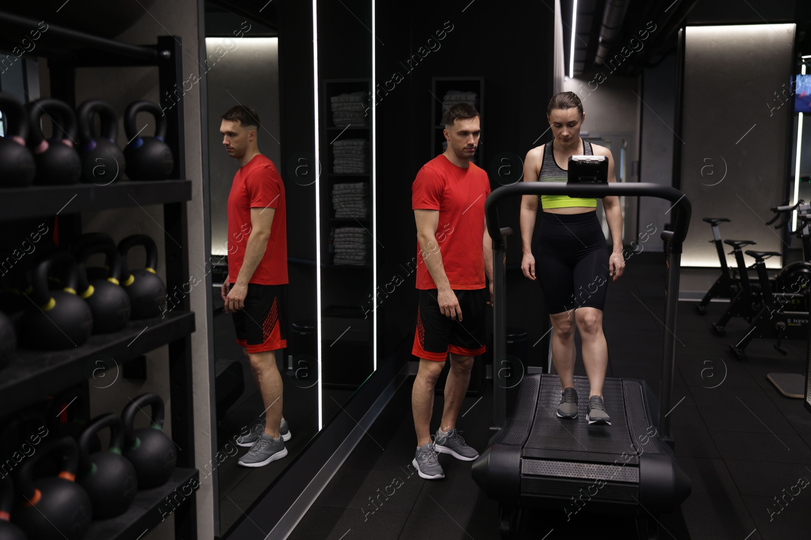 Young woman exercising on treadmill with professional personal trainer in gym Photo of Young woman exercising on treadmill with professional personal trainer in gym