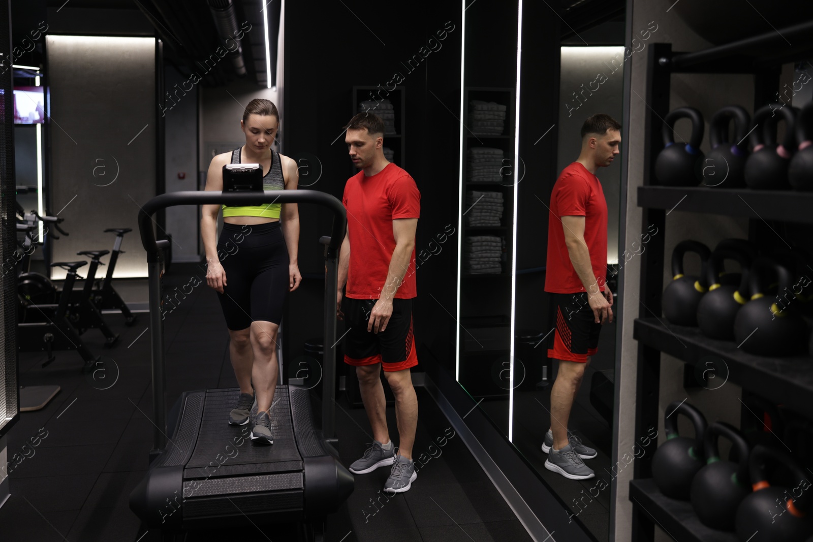 Young woman exercising on treadmill with professional personal trainer in gym Photo of Young woman exercising on treadmill with professional personal trainer in gym