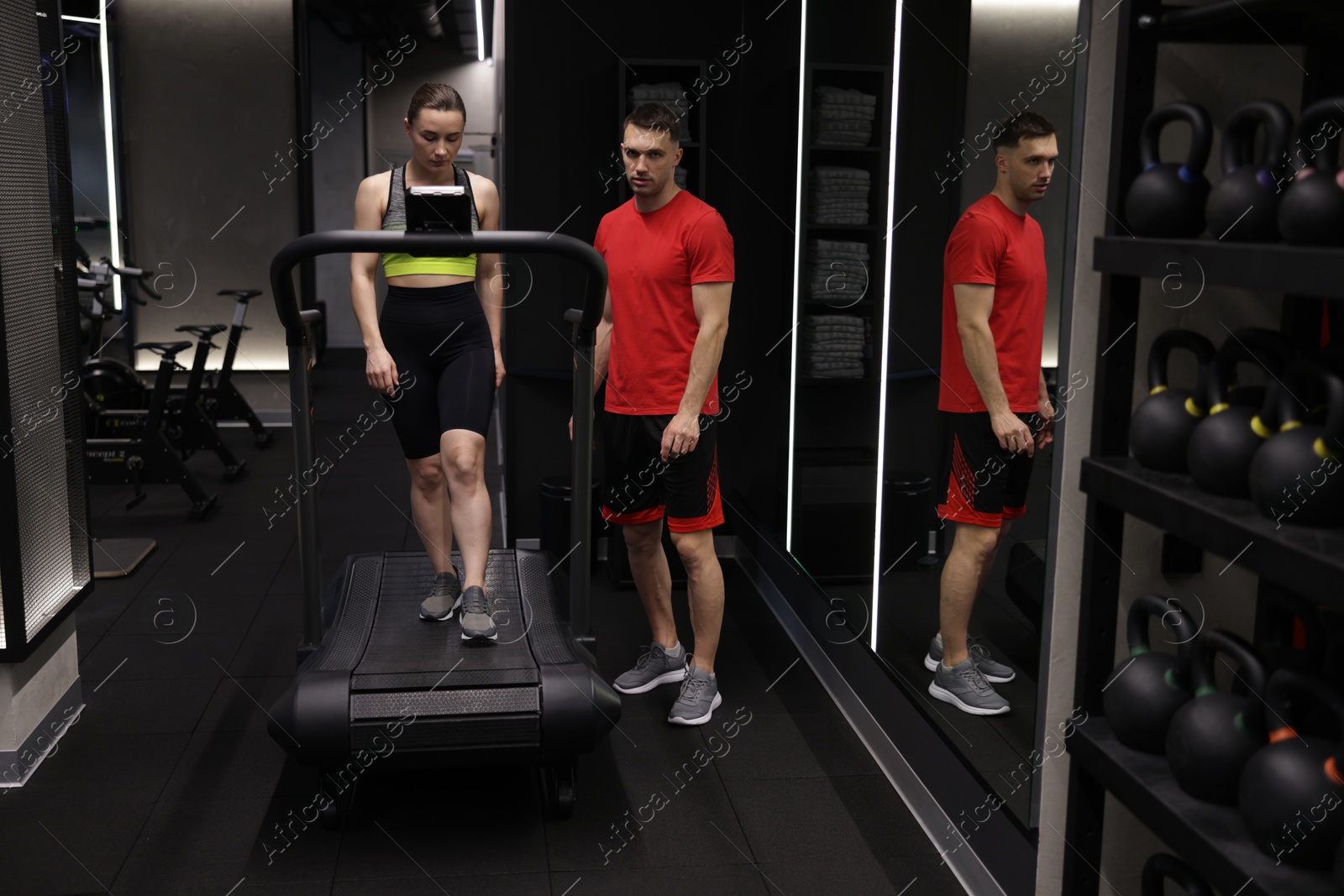 Young woman exercising on treadmill with professional personal trainer in gym Photo of Young woman exercising on treadmill with professional personal trainer in gym