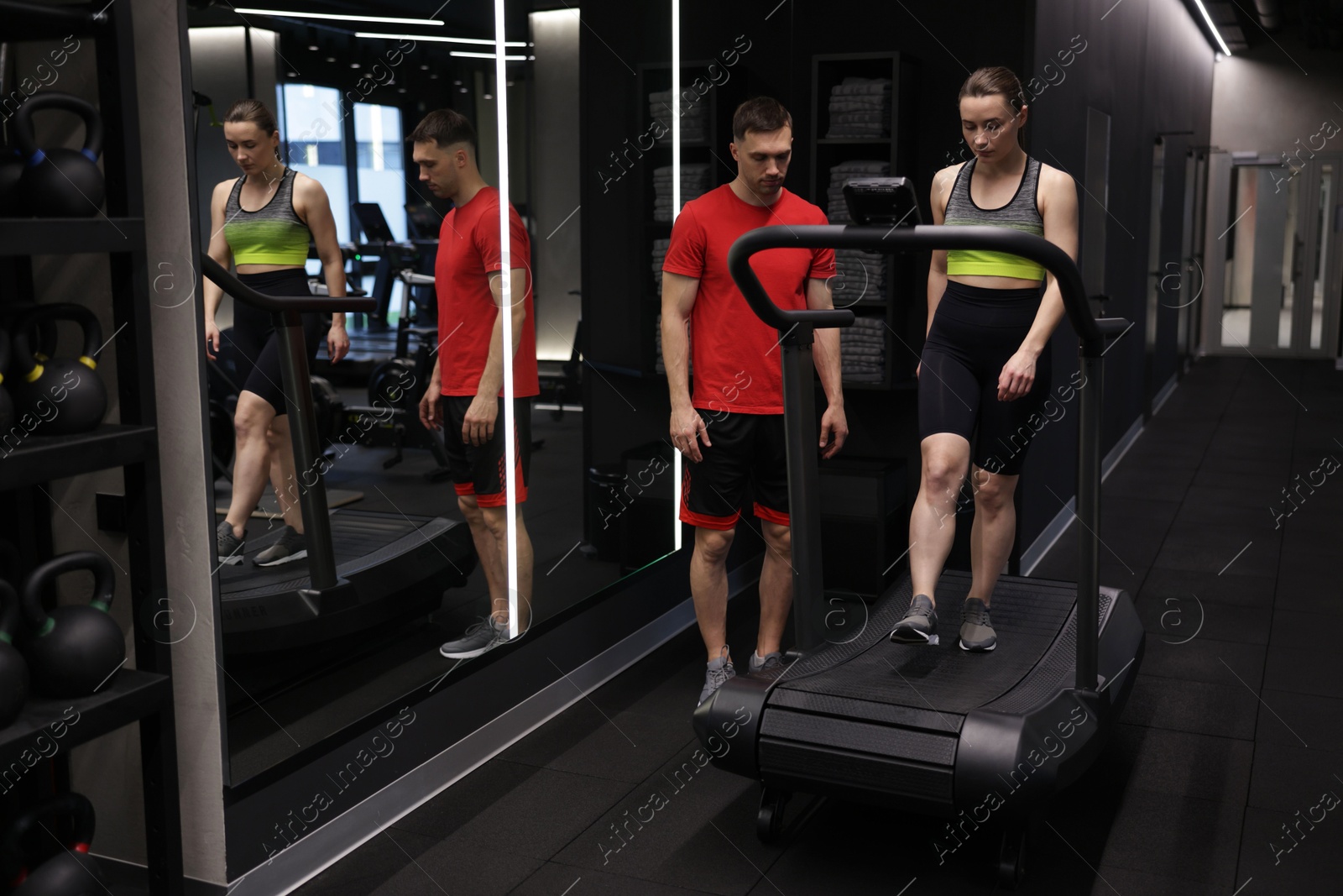 Young woman exercising on treadmill with professional personal trainer in gym Photo of Young woman exercising on treadmill with professional personal trainer in gym