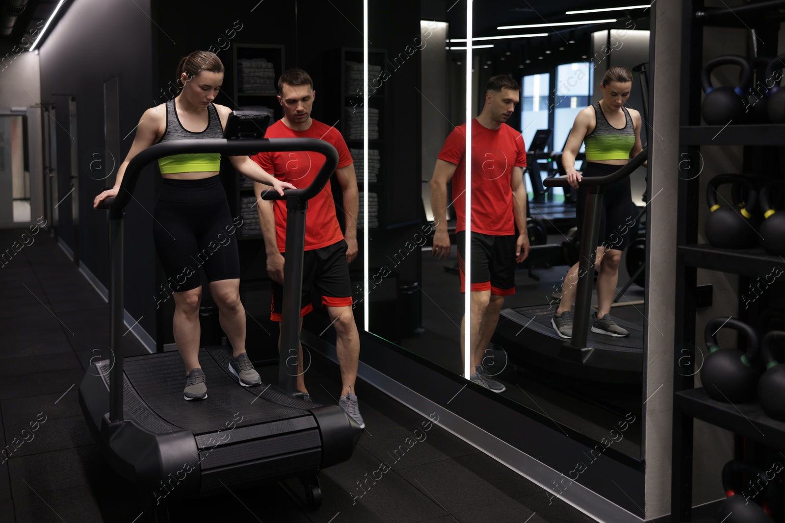 Young woman exercising on treadmill with professional personal trainer in gym Photo of Young woman exercising on treadmill with professional personal trainer in gym