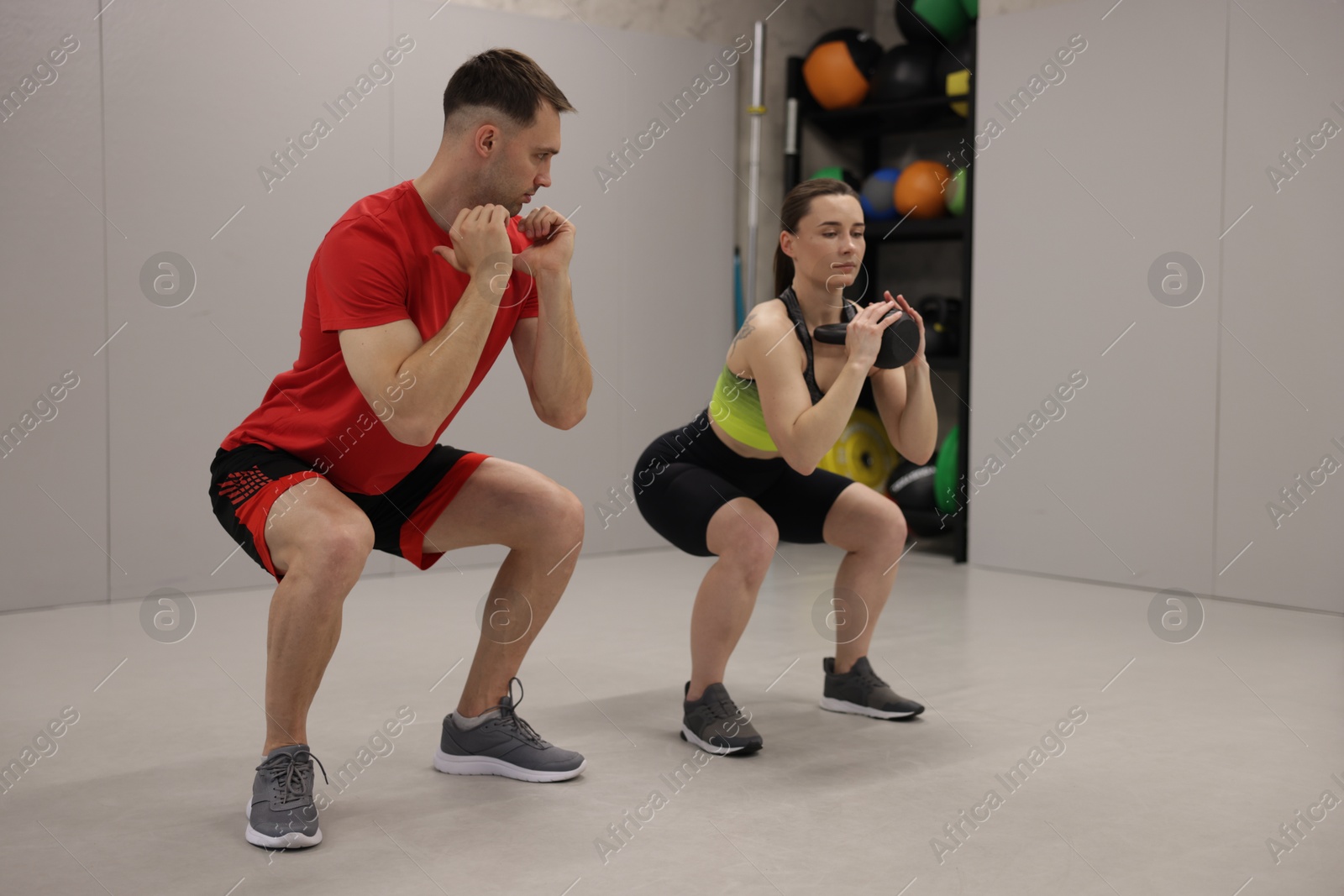 Young woman exercising with kettlebell with professional personal trainer in gym Photo of Young woman exercising with kettlebell with professional personal trainer in gym