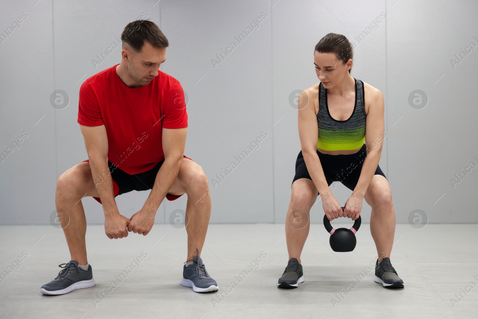 Young woman exercising with kettlebell with professional personal trainer in gym Photo of Young woman exercising with kettlebell with professional personal trainer in gym