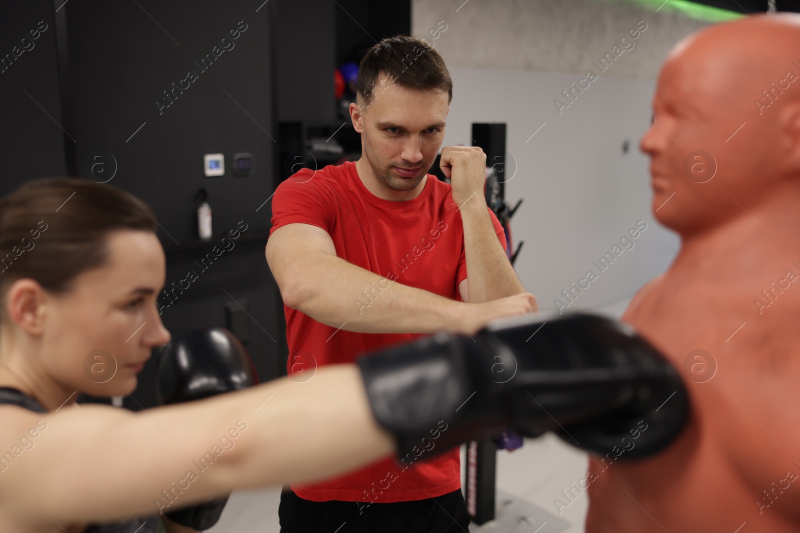 Young woman exercising with punching dummy with professional personal trainer in gym Photo of Young woman exercising with punching dummy with professional personal trainer in gym
