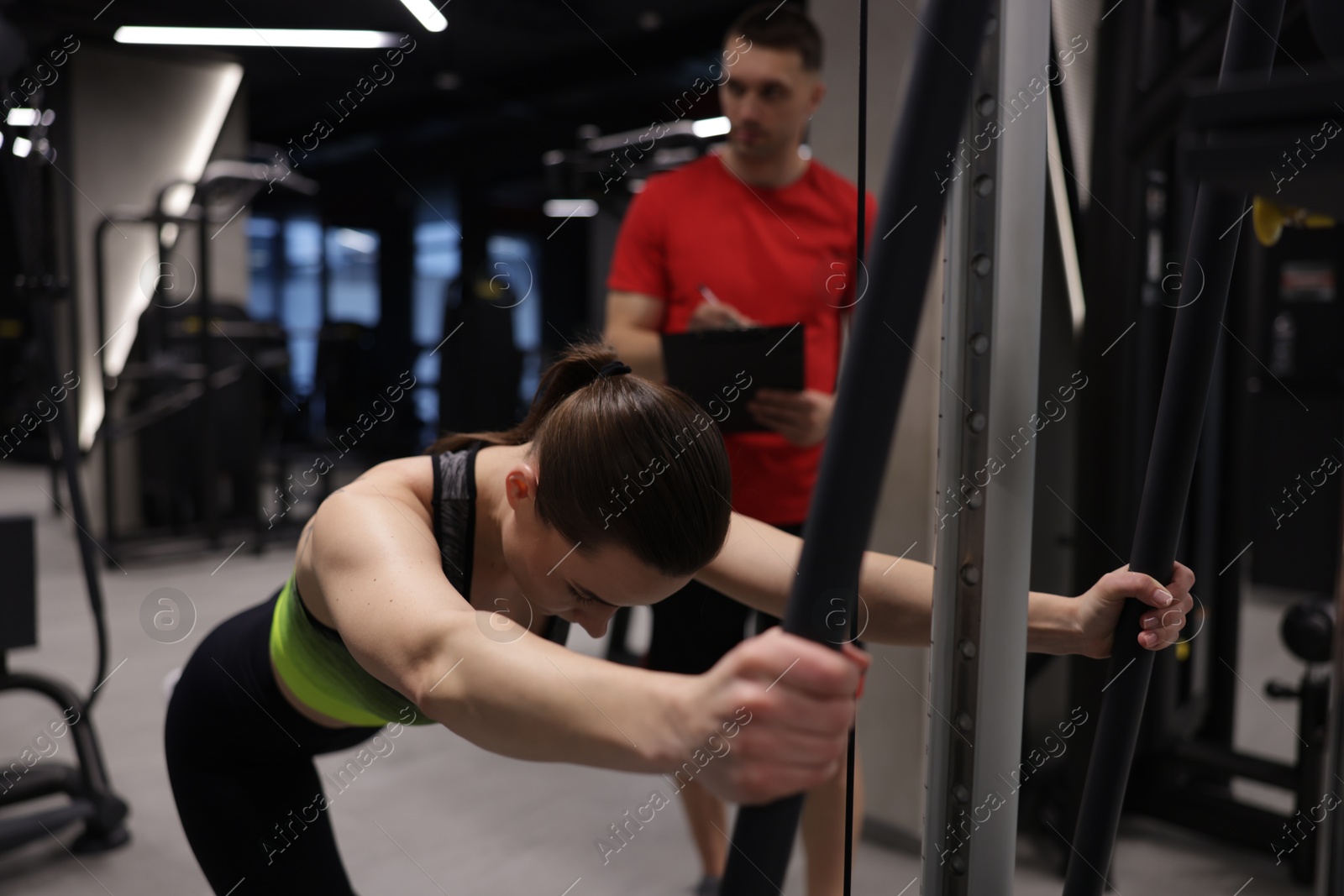Young woman exercising with cable machine with professional personal trainer in gym Photo of Young woman exercising with cable machine with professional personal trainer in gym