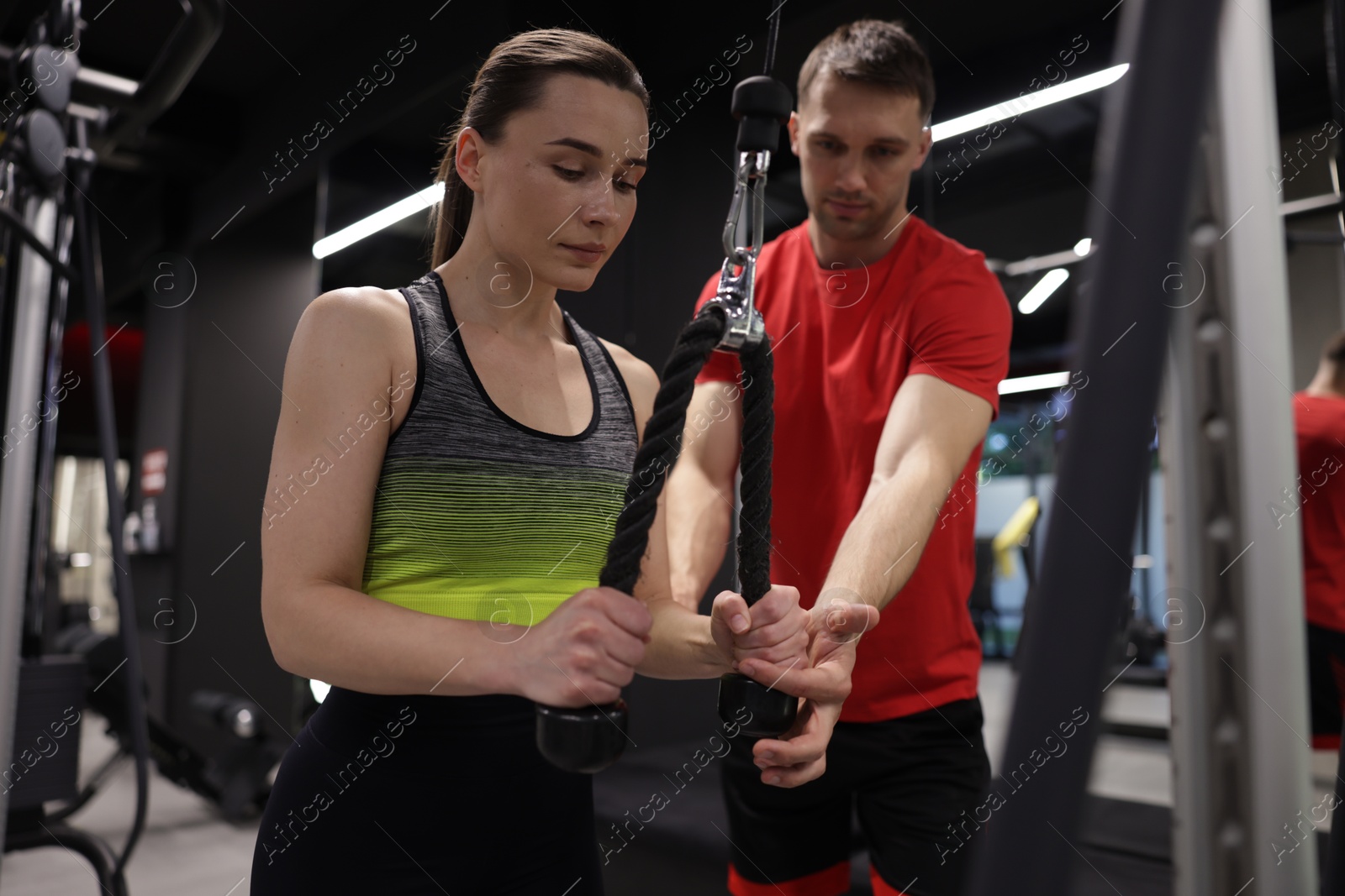Young woman exercising with lat pulldown machine with professional personal trainer in gym Photo of Young woman exercising with lat pulldown machine with professional personal trainer in gym