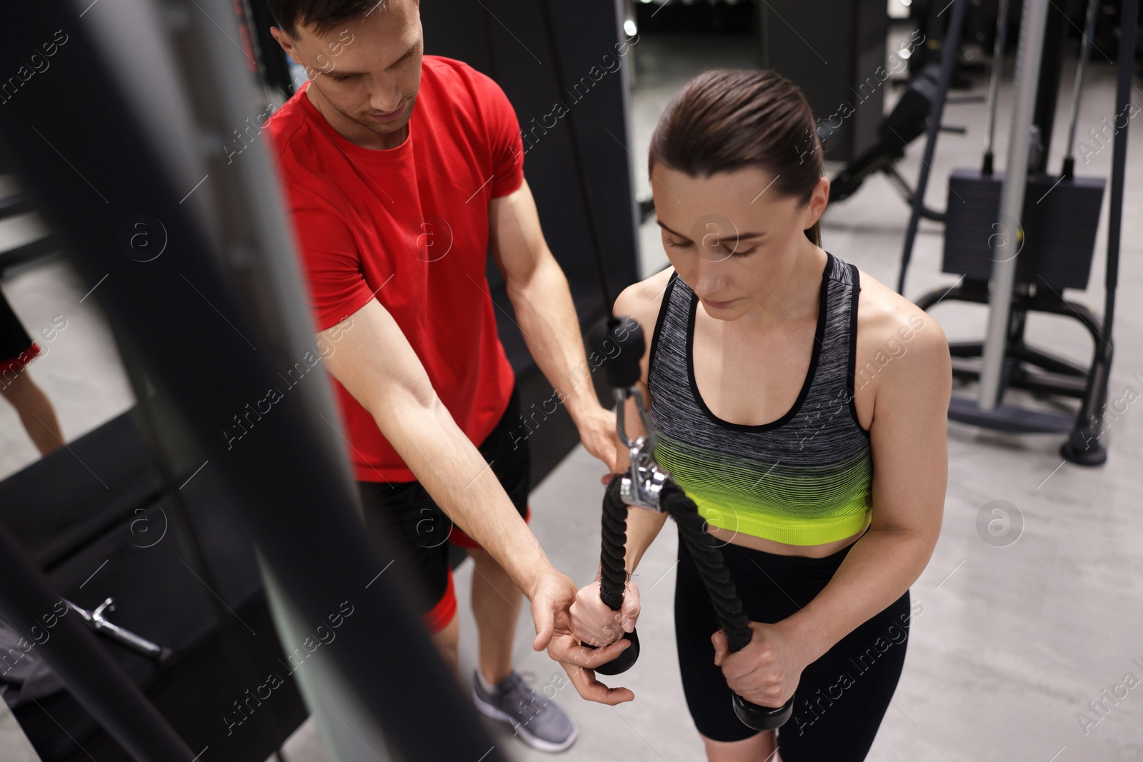 Young woman exercising with lat pulldown machine with professional personal trainer in gym Photo of Young woman exercising with lat pulldown machine with professional personal trainer in gym