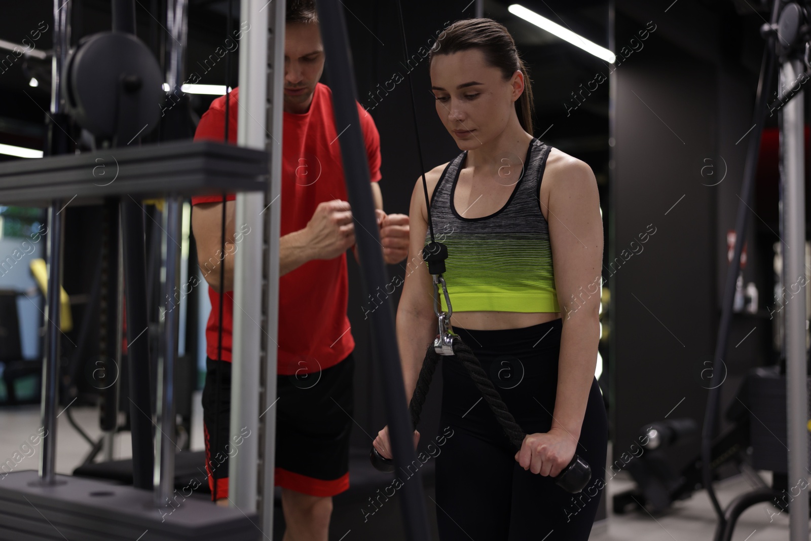 Young woman exercising with lat pulldown machine with professional personal trainer in gym Photo of Young woman exercising with lat pulldown machine with professional personal trainer in gym