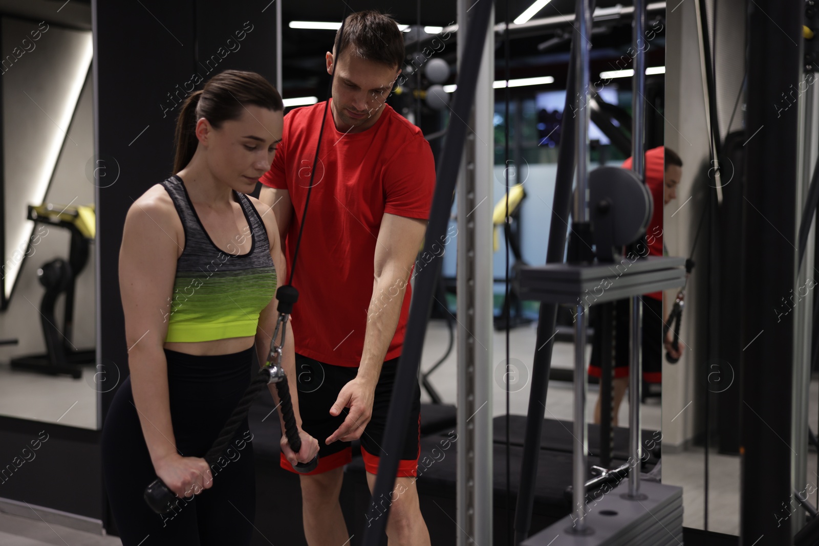 Young woman exercising with lat pulldown machine with professional personal trainer in gym Photo of Young woman exercising with lat pulldown machine with professional personal trainer in gym