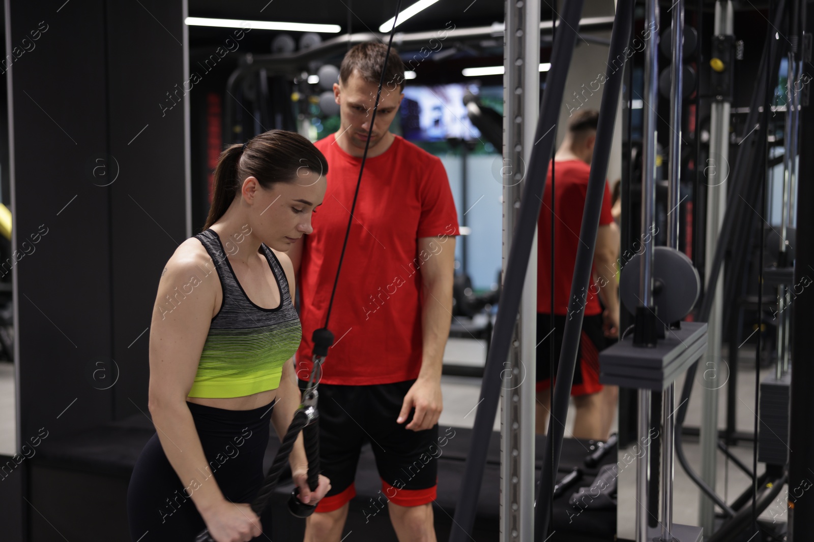 Young woman exercising with lat pulldown machine with professional personal trainer in gym Photo of Young woman exercising with lat pulldown machine with professional personal trainer in gym