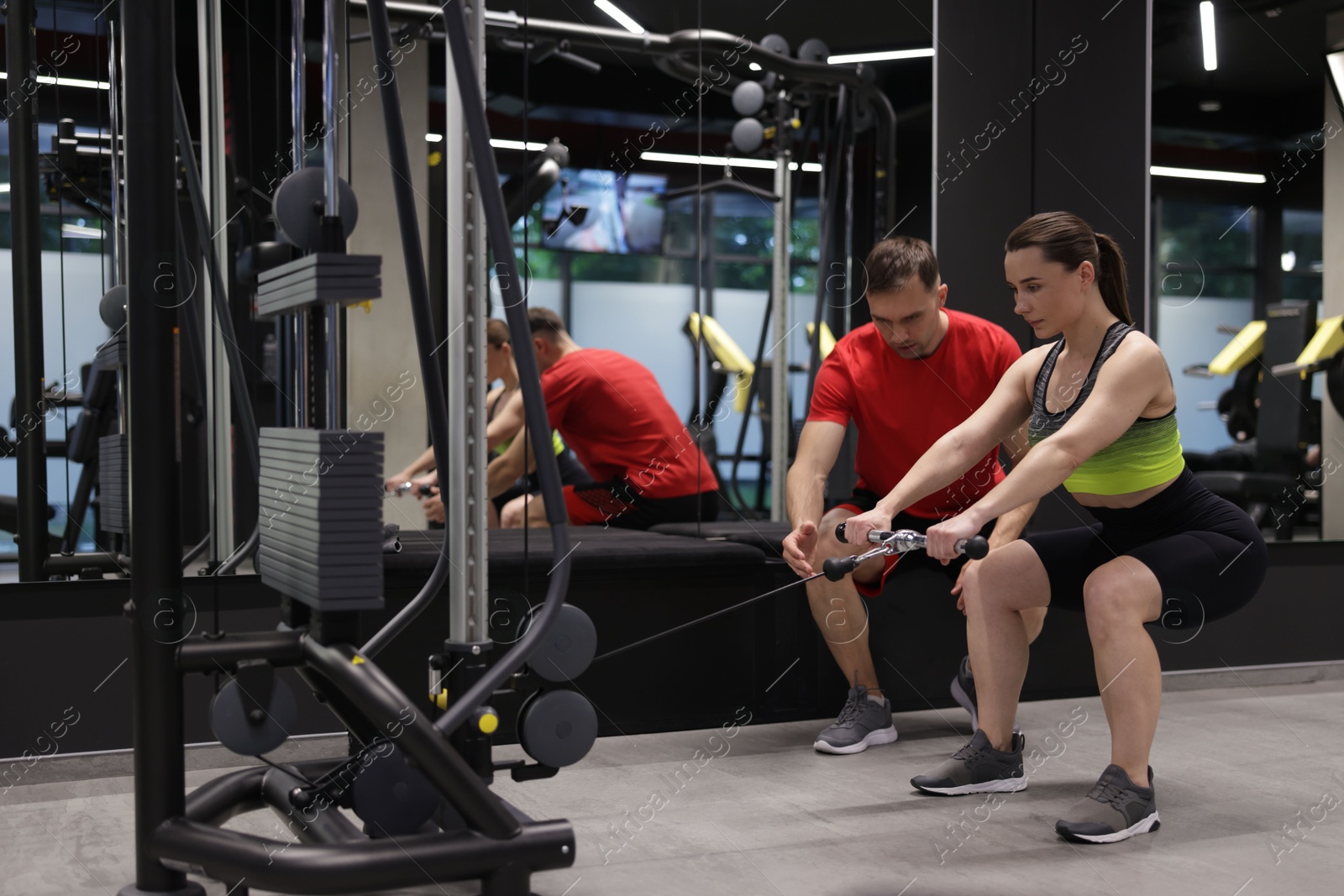Young woman exercising with cable machine with professional personal trainer in gym Photo of Young woman exercising with cable machine with professional personal trainer in gym