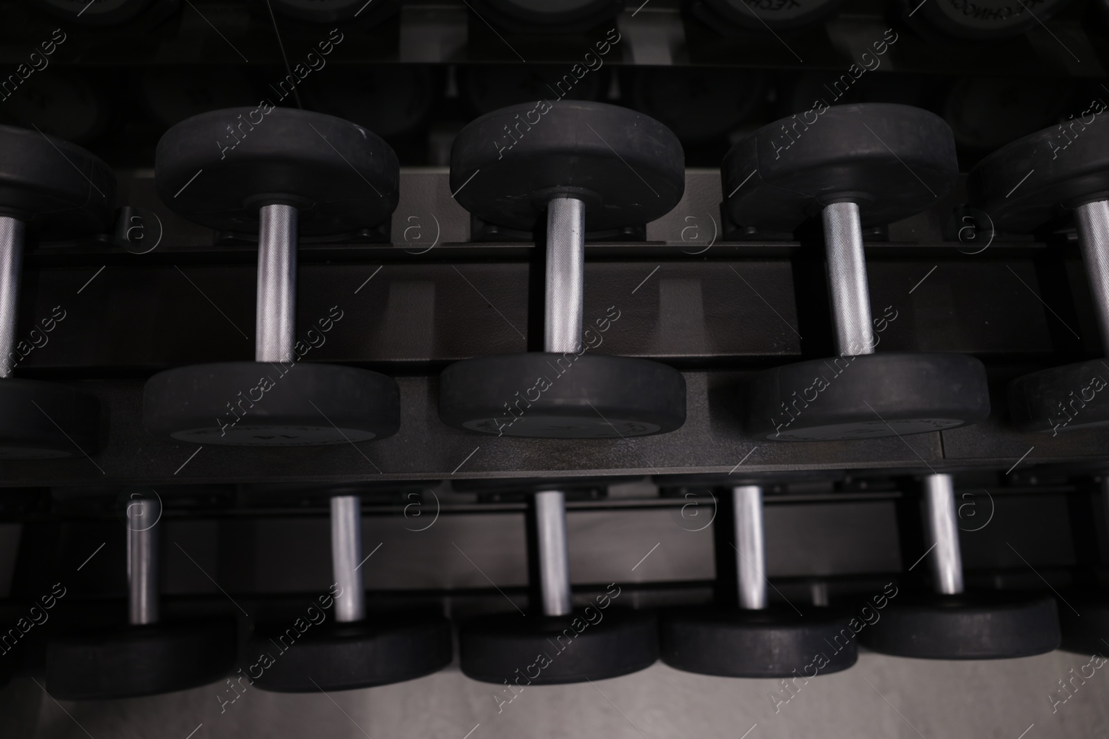 Many metal dumbbells on stand in gym, above view Photo of Many metal dumbbells on stand in gym, above view