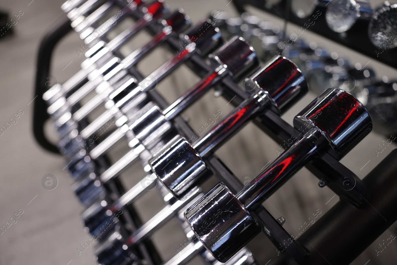 Many metal dumbbells on stand in gym, closeup Photo of Many metal dumbbells on stand in gym, closeup