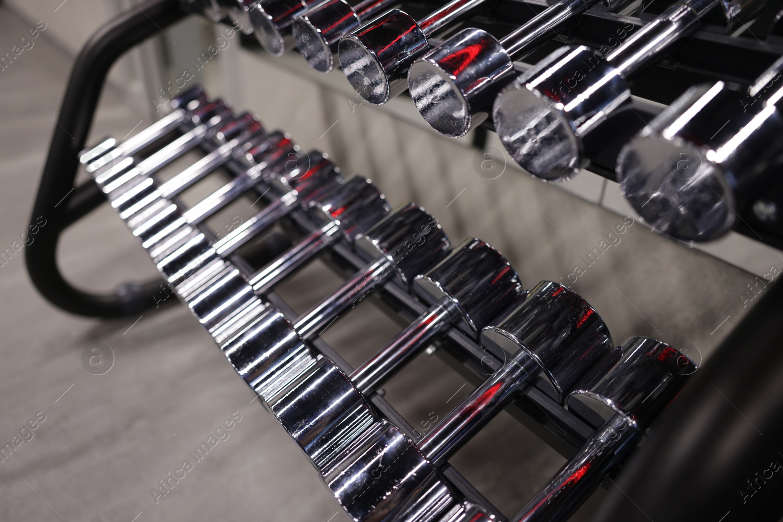 Many metal dumbbells on stand in gym, closeup Photo of Many metal dumbbells on stand in gym, closeup