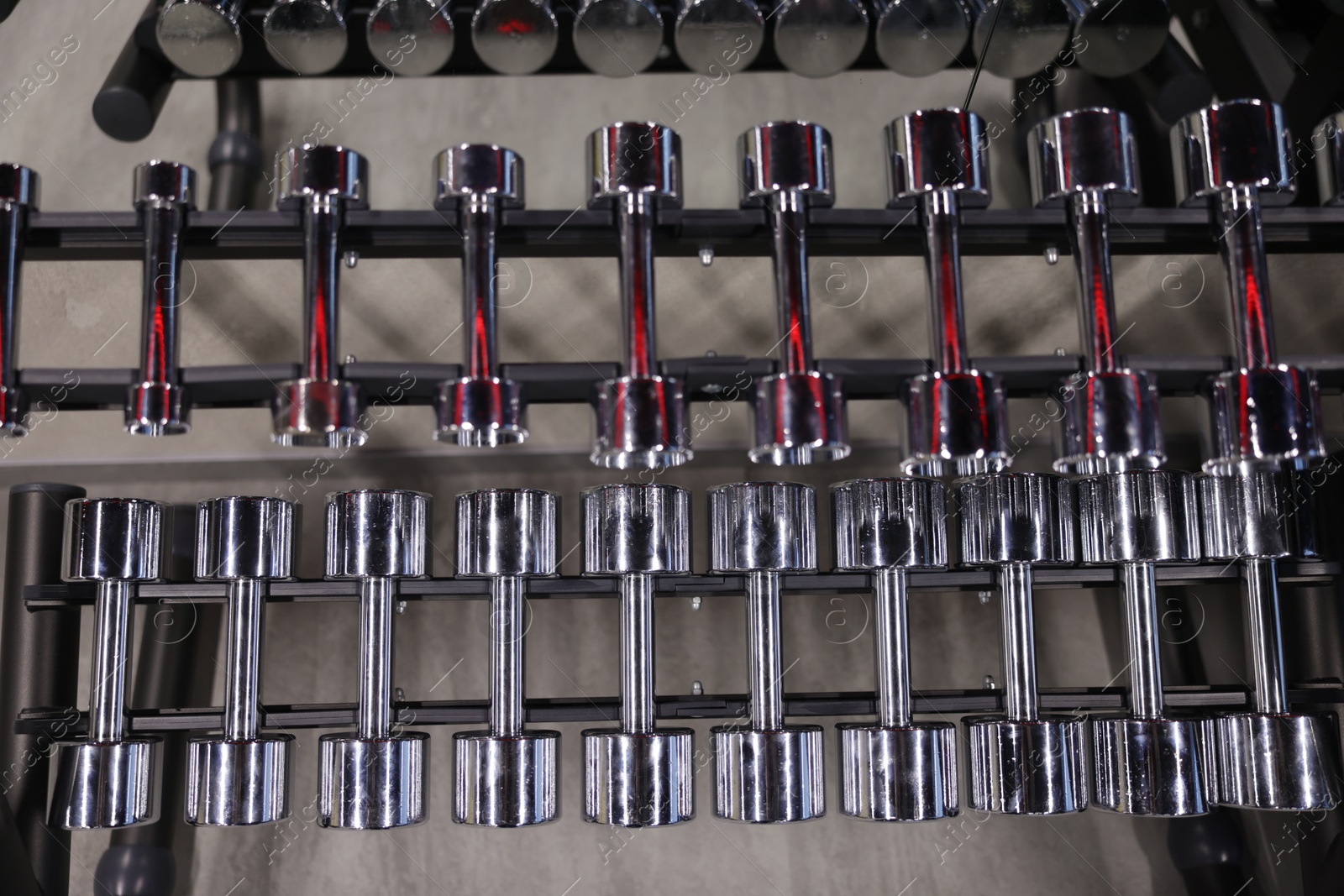Many metal dumbbells on stand in gym, above view Photo of Many metal dumbbells on stand in gym, above view