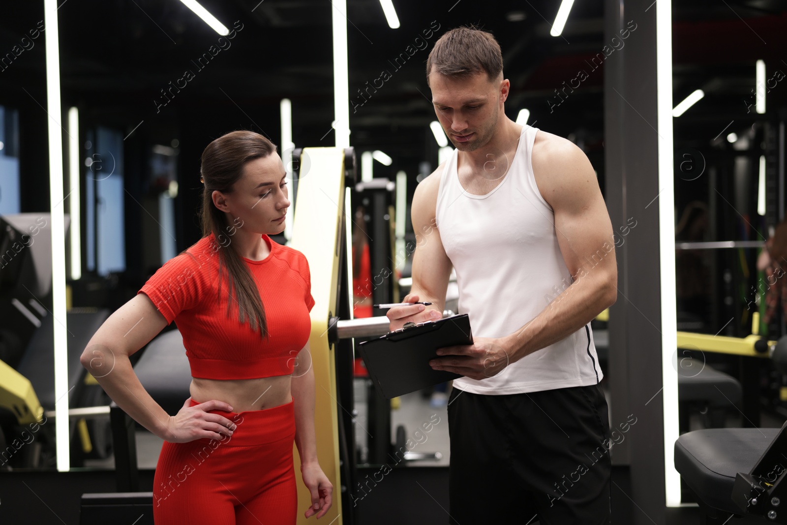 Young woman with professional personal trainer in gym Photo of Young woman with professional personal trainer in gym