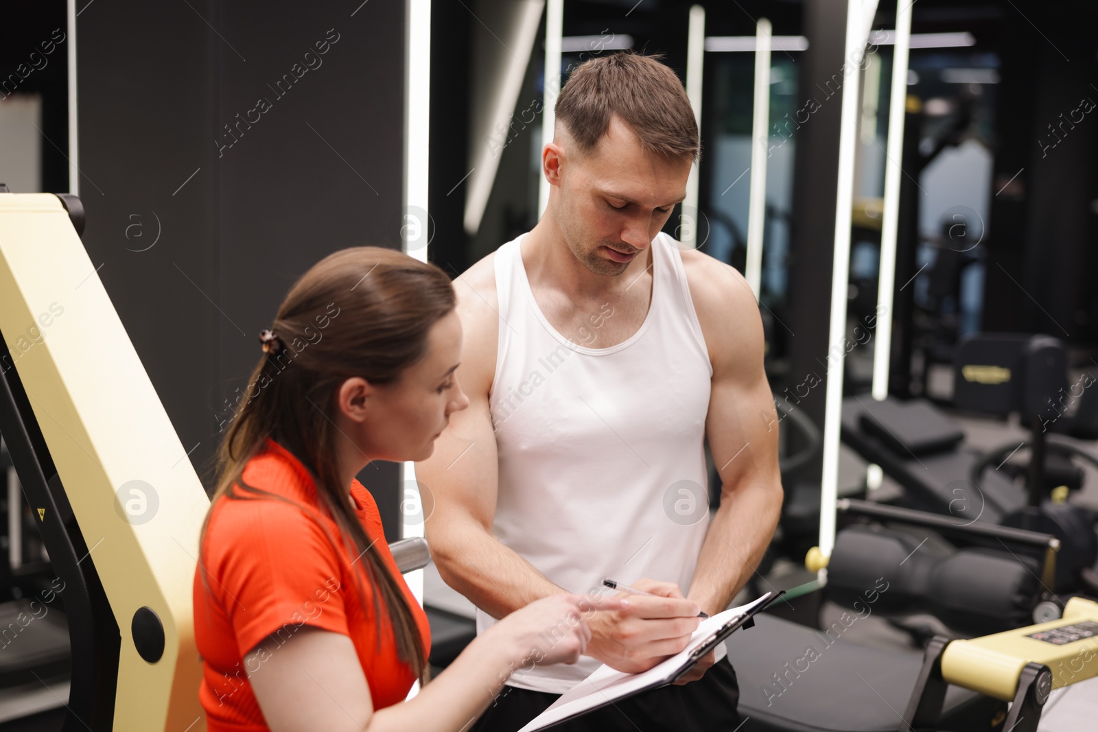 Young woman with professional personal trainer in gym Photo of Young woman with professional personal trainer in gym