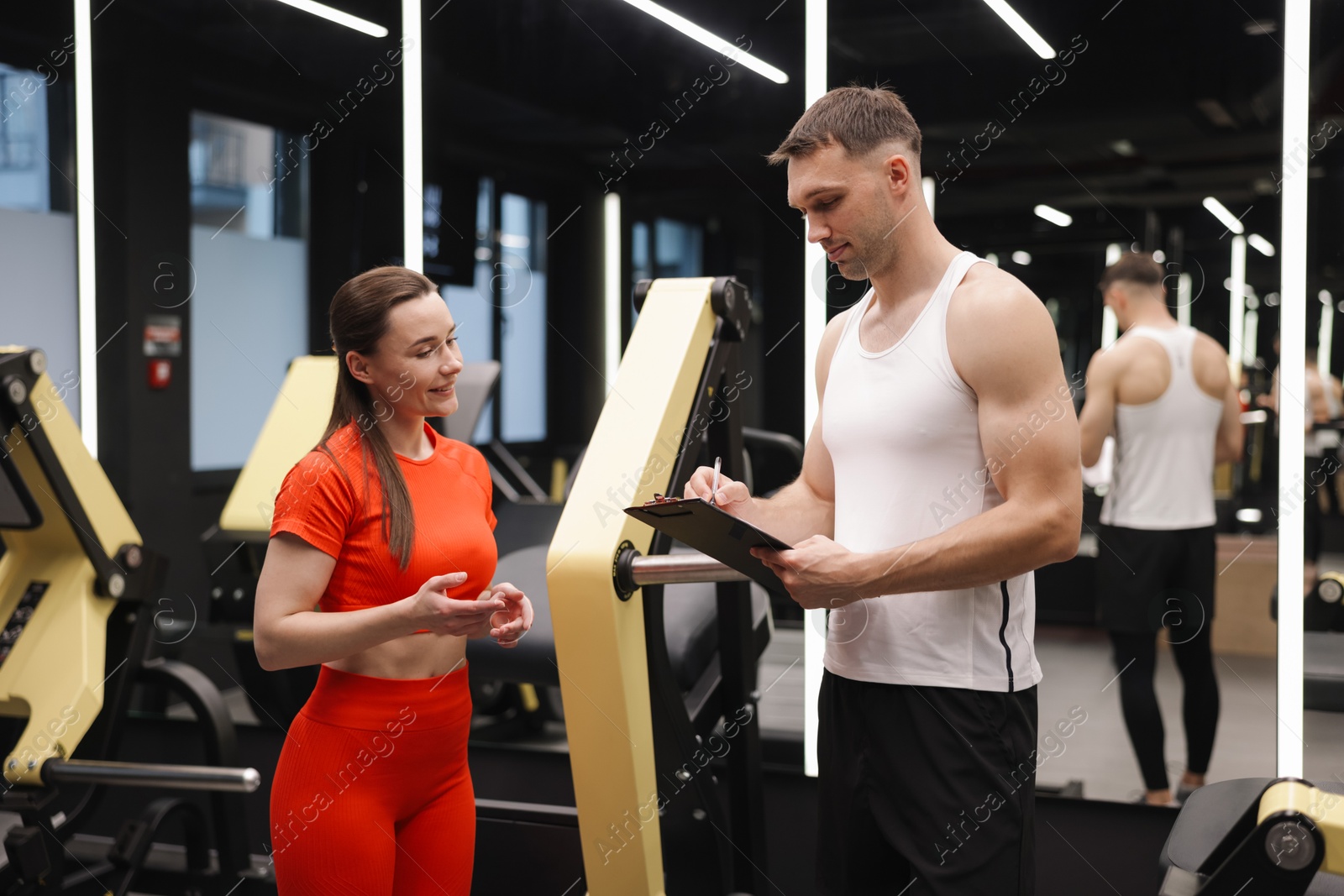 Young woman with professional personal trainer in gym Photo of Young woman with professional personal trainer in gym