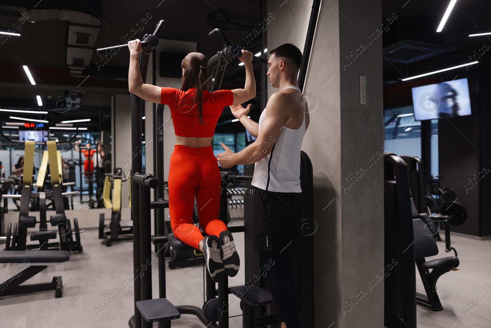 Young woman exercising with professional personal trainer in gym, back view Photo of Young woman exercising with professional personal trainer in gym, back view