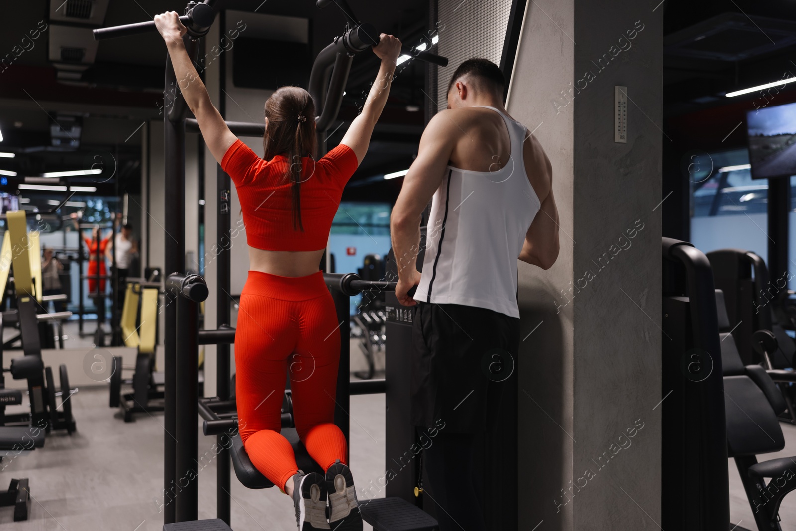 Young woman exercising with professional personal trainer in gym, back view Photo of Young woman exercising with professional personal trainer in gym, back view