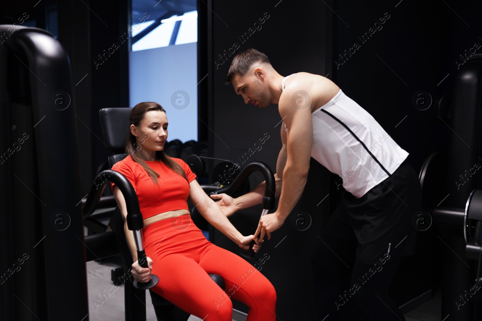 Young woman exercising with pull down machine professional personal trainer in gym Photo of Young woman exercising with pull down machine professional personal trainer in gym