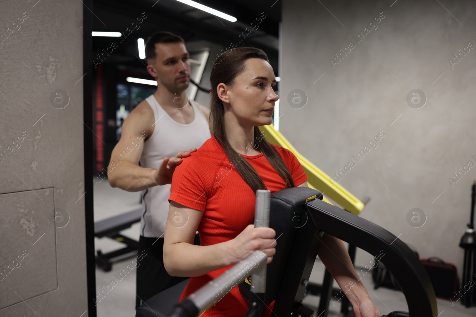 Young woman exercising on seated row machine with professional personal trainer in gym Photo of Young woman exercising on seated row machine with professional personal trainer in gym