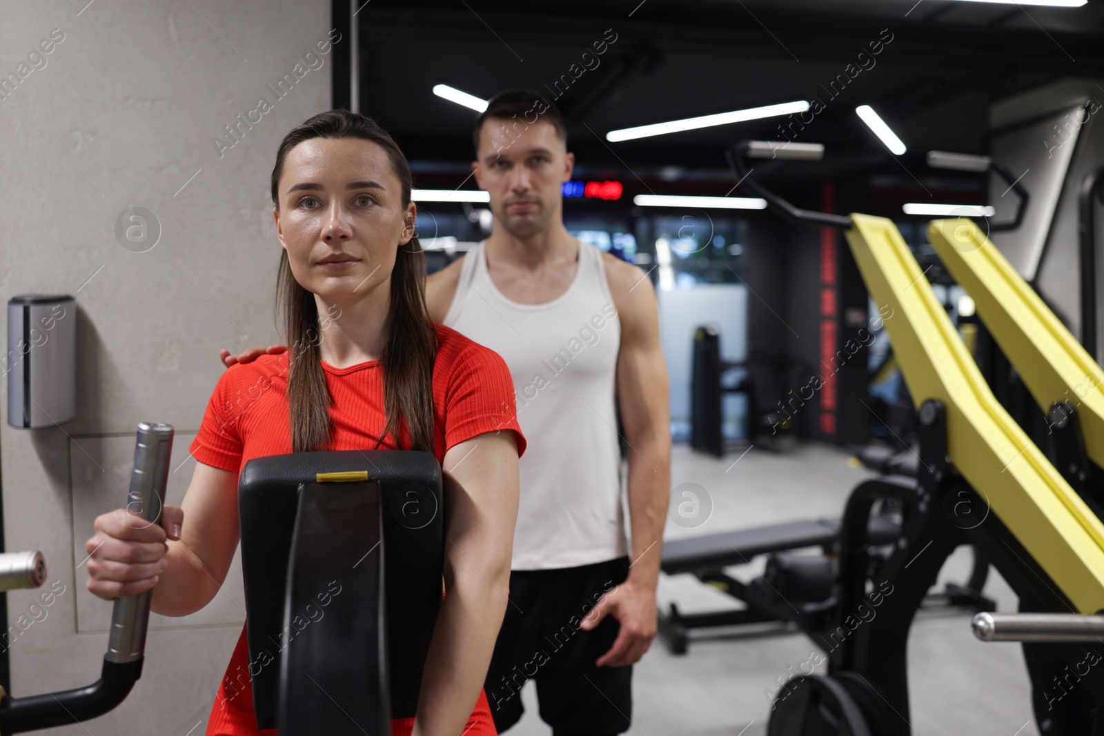 Young woman exercising on seated row machine with professional personal trainer in gym Photo of Young woman exercising on seated row machine with professional personal trainer in gym