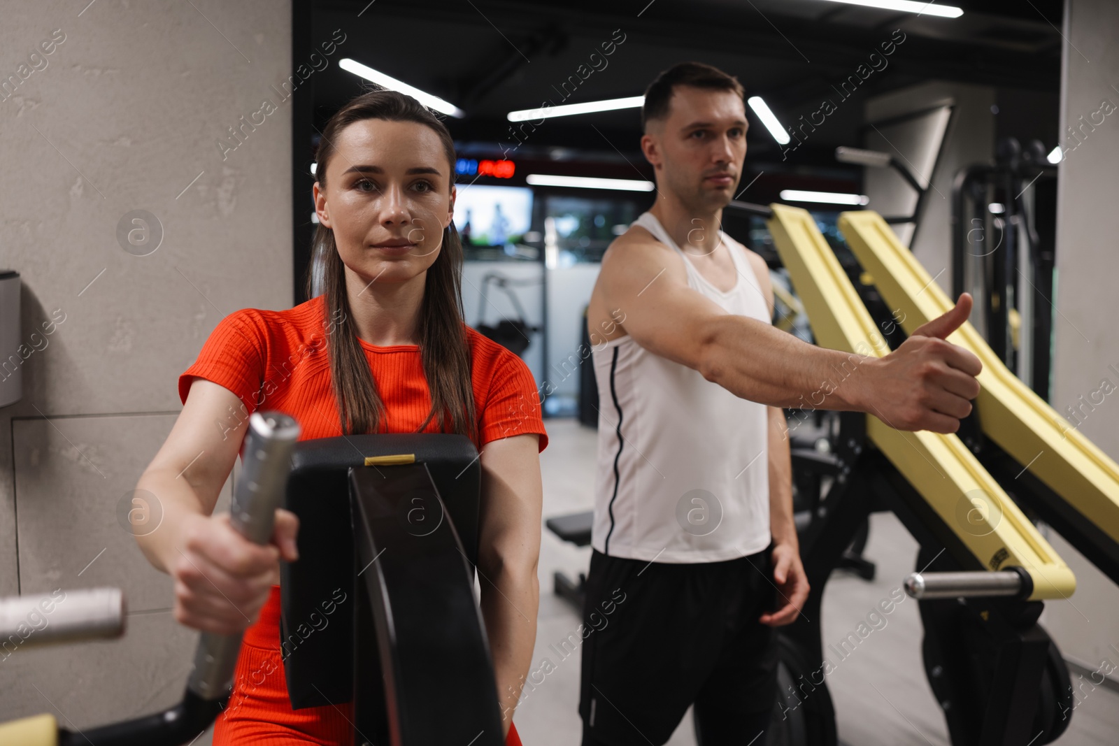 Young woman exercising on seated row machine with professional personal trainer in gym Photo of Young woman exercising on seated row machine with professional personal trainer in gym