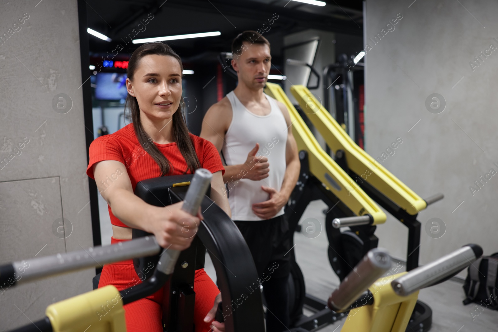 Young woman exercising on seated row machine with professional personal trainer in gym Photo of Young woman exercising on seated row machine with professional personal trainer in gym
