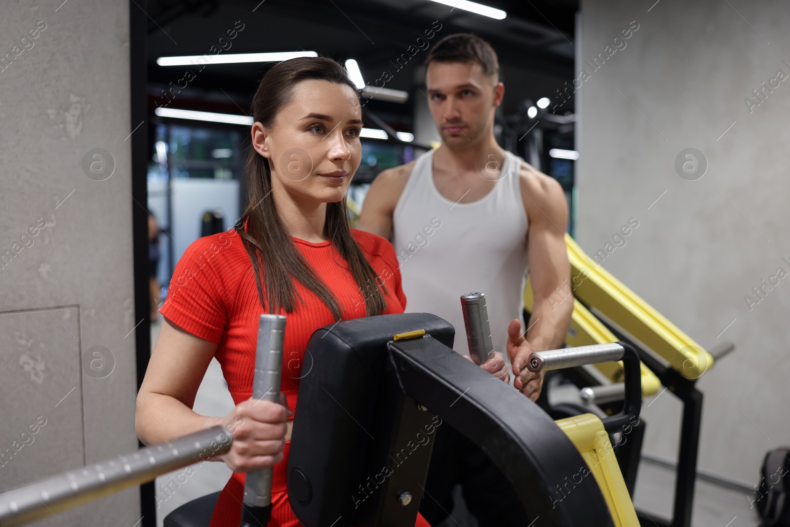 Young woman exercising on seated row machine with professional personal trainer in gym Photo of Young woman exercising on seated row machine with professional personal trainer in gym