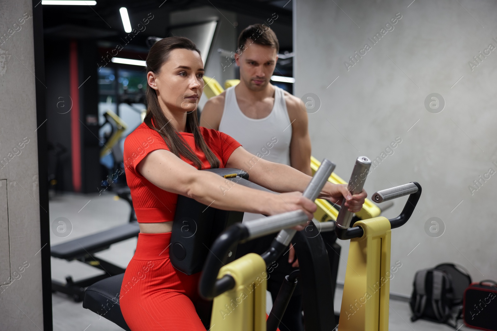 Young woman exercising on seated row machine with professional personal trainer in gym Photo of Young woman exercising on seated row machine with professional personal trainer in gym