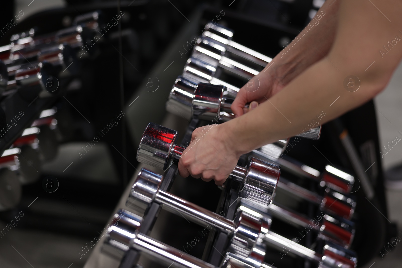 Woman taking dumbbells from stand in gym, closeup Photo of Woman taking dumbbells from stand in gym, closeup
