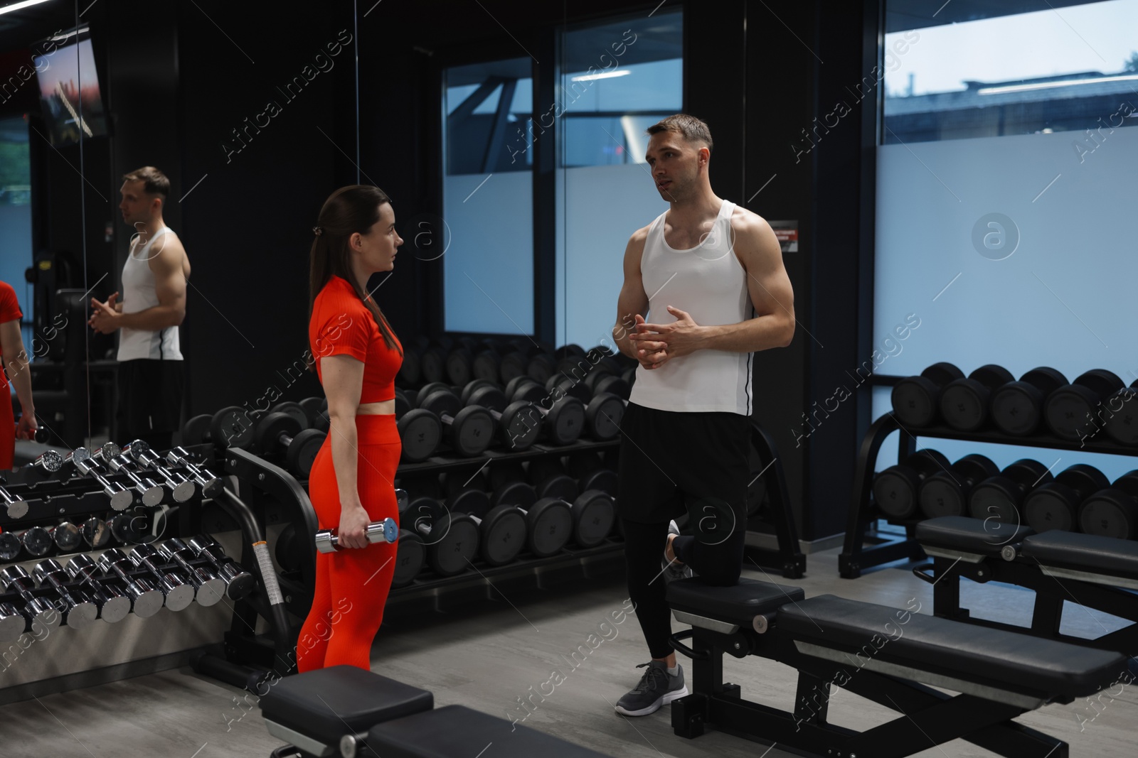 Young woman exercising with dumbbells with professional personal trainer in gym Photo of Young woman exercising with dumbbells with professional personal trainer in gym