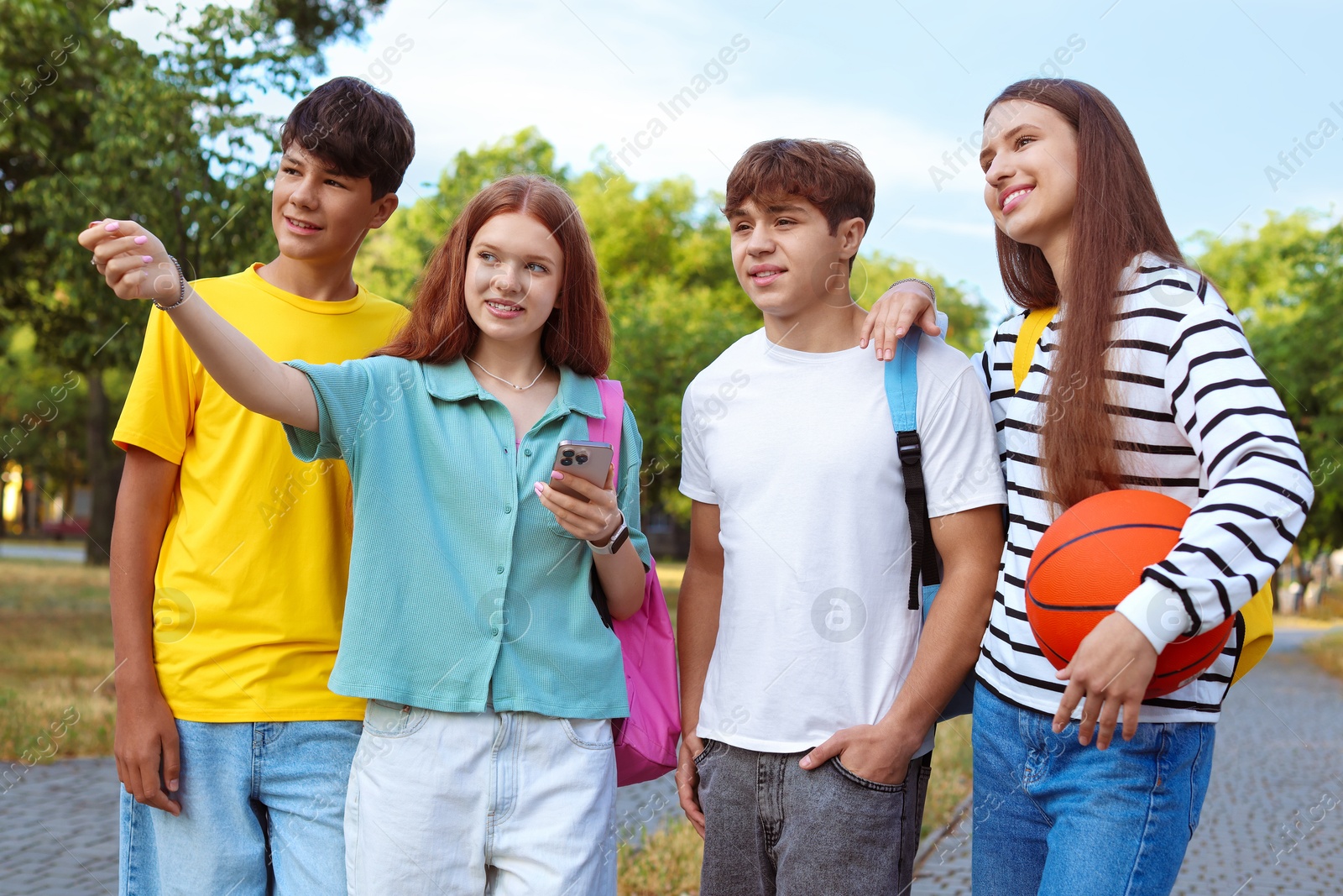 Group of teenagers walking together in park Photo of Group of teenagers walking together in park