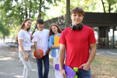 Photo of Portrait of teenage boy with headphones in park, selective focus