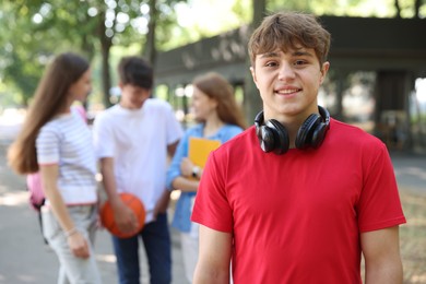 Photo of Portrait of teenage boy with headphones in park, selective focus